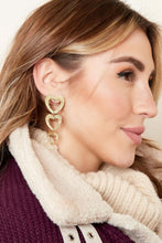 Load image into Gallery viewer, Gouden oorbellen met bedels in de vorm van drie hartjes! De hartjes zijn voorzien van structuur waardoor de oorbellen er luxe uitzien! De totale afmeting van de oorbellen is 6,5 cm, perfect om deze oorbellen als statement sieraad te dragen! Oorbellen zijn gemaakt van stainless steel.