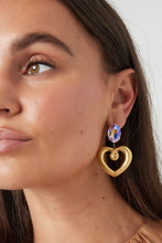 Afbeelding in Gallery-weergave laden, Gouden oorbellen met glaskraal en bedel in de vorm van een hart. De oorbellen zijn mega trendy en zijn perfect te combineren met meerdere gouden sieraden. De oorbellen zijn gemaakt van Stainless steel in combinatie met glaskralen en hebben een afmeting van 4,98 cm. Wauw! Wat een prachtige statement oorbellen.