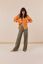 Afbeelding in Gallery-weergave laden, Corel Broek Lily Wide Jaquard Circle heeft een subtiele glans in de kleurencombinatie groen en oranje. Een broek met rechte losvallende pijpen en paspelzakken op de achterkant en groene knoopjes. Het patroon geeft een chique maar eigentijdse uitstraling. Een broek met dé perfecte en zeer mooie vrouwelijke pasvorm.