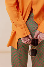 Afbeelding in Gallery-weergave laden, Corel Broek Lily Wide Jaquard Circle heeft een subtiele glans in de kleurencombinatie groen en oranje. Een broek met rechte losvallende pijpen en paspelzakken op de achterkant en groene knoopjes. Het patroon geeft een chique maar eigentijdse uitstraling. Een broek met dé perfecte en zeer mooie vrouwelijke pasvorm.