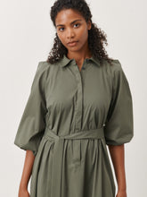 Afbeelding in Gallery-weergave laden, Groene Jurk Carlen ES92421115 van Jane Lushka is een sportieve korte wijde jurk van katoen met kraag en bedekte knoopjes tot halverwege jurk. Jurk heeft 3/4 pofmouwen met elastiek en steekzakken aan beide kanten. Deze jurk heeft geen lusjes, maar wel een lange ceintuur in dezelfde stof voor een nonchalant effect, ook zonder ceintuur te dragen. De Carlen Jurk draagt erg comfortabel door het soepele katoen en is goed te dragen voor elke gelegenheid. Het model is 1,79 cm lang en draagt maat S.
