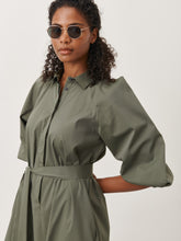 Afbeelding in Gallery-weergave laden, Groene Jurk Carlen ES92421115 van Jane Lushka is een sportieve korte wijde jurk van katoen met kraag en bedekte knoopjes tot halverwege jurk. Jurk heeft 3/4 pofmouwen met elastiek en steekzakken aan beide kanten. Deze jurk heeft geen lusjes, maar wel een lange ceintuur in dezelfde stof voor een nonchalant effect, ook zonder ceintuur te dragen. De Carlen Jurk draagt erg comfortabel door het soepele katoen en is goed te dragen voor elke gelegenheid. Het model is 1,79 cm lang en draagt maat S.