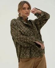 Load image into Gallery viewer, Blouse van Moment Amsterdam met referentie 57.100-23, is een prachtige romantische blouse met bloemenprint. Deze blouse heeft een opstaande kraag met ruffles aan de hals en mouwen. Deze blouse is mooi te combineren met de Corel Broek Lily Wide Uni Sport.