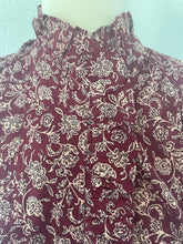 Load image into Gallery viewer, Wijnrode Blouse van Moment Amsterdam met referentie 57.100-23, is een prachtige romantische blouse met bloemenprint. Deze blouse heeft een opstaande kraag met ruffles aan de hals en mouwen. Deze blouse is mooi te combineren met de Corel Broek Lily Wide Uni Sport Beetroot.