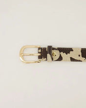 Afbeelding in Gallery-weergave laden, Cow Riem Evie is gemaakt van 100% Italiaans leer en heeft een trendy koeienprint en een goudkleurige gesp. De riem is gemakkelijk korter te maken door middel van een schroef.