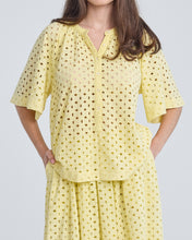 Load image into Gallery viewer, Gele Blouse Top Blanca van de Moment Amsterdam Collectie is een top met een ronde hals en een korte vlindermouw in een prachtige zomerse kleur. Deze katoenen blouse top heeft knoopjes tot halverwege de blouse en een gaatjes patroon met geborduurde bloemen.
