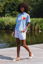 Afbeelding in Gallery-weergave laden, Gestreepte Blouse Now or Never Wit is een zomerse blouse van 100% katoen met korte mouwen en kraag. De voorkant van deze blouse heeft een rood hart en de achterkant is voorzien van een kleurrijke opdruk 'Now or Never'.