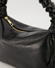 Afbeelding in Gallery-weergave laden, Zwarte Lederen handtas met een gerimpeld handvat als mooi detail, in een metallic uitvoering. De tas heeft een hoofdvak met ritssluiting en aan de binnenzijde een ritsvakje. Tas Raina is verkrijgbaar in verschillende kleuren: Metallic Zwart, Metallic Zilver en heeft een afmeting van : 28cm x 17cm x 8cm.