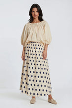 Load image into Gallery viewer, Maxi Rok Norma is een elegante, zachtgele lange rok met speelse donkerblauwe stippen. De rok heeft een comfortabele elastische tailleband, waardoor hij mooi aansluit en prettig draagt. Dankzij de praktische steekzakken combineert Rok Norma stijl met gemak, perfect voor zowel een casual als een meer geklede look.