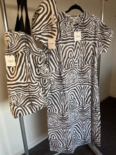 Load image into Gallery viewer, Zomerjurk, Kaftan van Moment by Moment in een vale zwart/wit print in zebra dessin. Zomerjurk heeft een ronde hals met vier knoopjes en heeft steekzakken. In deze serie is verkrijgbaar: Zomerjurk, super grote strandtas, te sluiten met een strikje en een mini tasje met rits. Met deze prachtige set ben je helemaal klaar voor het strand of het terras. De kaftan/zomerjurk is ook los verkrijgbaar.