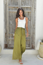 Afbeelding in Gallery-weergave laden, De olijfgroene Broek Luana uit de Hot Lava collectie combineert comfort en stijl in één elegante look. Deze satijnen broek heeft een soepelvallende stof en wijde pijpen die zorgen voor een vrouwelijke, nonchalante uitstraling.
De broek is voorzien van handige steekzakken, een strikceintuur en een elastische doorgestikte tailleband voor een comfortabele pasvorm. Dankzij de luchtige fit en luxe satijnglans is Broek Luana perfect voor zowel een casual als chic te stylen outfit.