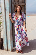Afbeelding in Gallery-weergave laden, Multicolor Jurk, Maxi Dress Rosa Blue Bird Long van Place du Soleil in de kleurstelling wit, blauw en fuchsia. De Rosa Blue Bird Long Dress is een prachtig uitlopende lange gevoerde jurk met steekzakken en heeft een smallere taille met (vaste) ceintuur met oranje fluo flosjes. Jurk heeft een V-hals met fluo oranje borduursel en korte mouwen, is afgezet met subtiele pailletten en is bewerkt met prachtig lurex draad.