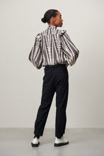 Afbeelding in Gallery-weergave laden, Zwart/witte Blouse Kim is een vrouwelijke blouse uit de collectie van Jane Luskha, heeft lange mouwen met bredere manchetten, ruches op de schouders en een opstaande kraag. Deze stijlvolle blouse is ook ontzettend mooi om te dragen onder een zwart pak. De blouse is van de bekende travel kwaliteit en is verkrijgbaar in verschillende maten. Item referentie : PEG723116