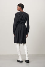 Afbeelding in Gallery-weergave laden, Zwarte Jurk Lizette is een klassieke jurk met lange mouwen van de Jane Luskha Collectie. Jurk heeft een V-hals aan de voorkant en een smal ceintuur van dezelfde stof (geen lussen) om de jurk te strikken en kleine splitjes aan beide zijden onderkant. Mooie jurk door eenvoud en voor vele gelegenheden te dragen. De jurk is uitgevoerd in de kleur zwart en is van de bekende travel kwaliteit.