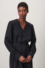 Afbeelding in Gallery-weergave laden, Zwarte Jurk Lizette is een klassieke jurk met lange mouwen van de Jane Luskha Collectie. Jurk heeft een V-hals aan de voorkant en een smal ceintuur van dezelfde stof (geen lussen) om de jurk te strikken en kleine splitjes aan beide zijden onderkant. Mooie jurk door eenvoud en voor vele gelegenheden te dragen. De jurk is uitgevoerd in de kleur zwart en is van de bekende travel kwaliteit.