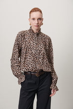 Load image into Gallery viewer, Jane Lushka Blouse Roberta is een verfijnde elegante maar een beetje speels blouse door de panterprint uit de collectie van Jane Lushka. Blouse heeft ruffles aan de voorkant, een hoge kraag, lange mouwen met elastiek en ruffles en heeft bruine knoopjes. Deze stijlvolle blouse is gewaagd en voor de zelfbewuste vrouw.