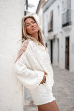 Load image into Gallery viewer, Off White Blouse Corazon van ibzmode heeft een ronde hoge hals, gerafelde details, heeft een kreukel effect in de stof, gehaakt net op de schouders, pofmouwen met elastiek bij de polsen, kan op de rug gestrikt worden, touwtjes met kwastjes en valt op de rug een klein stukje open. Dit is echt een prachtige top!