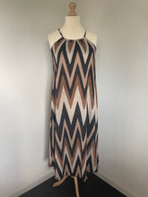 Load image into Gallery viewer, Jurk Maxi Viscose V Patroon is een lange jurk van viscose, in aardetinten met lurex. Jurk heeft veel stretch en zit heerlijk, heeft een ronde hals met elastiek en spaghettibandjes.
De jurk is one size en is te dragen van maat 36 t/m maat 44.