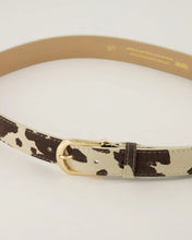 Afbeelding in Gallery-weergave laden, Cow Riem Evie is gemaakt van 100% Italiaans leer en heeft een trendy koeienprint en een goudkleurige gesp. De riem is gemakkelijk korter te maken door middel van een schroef.