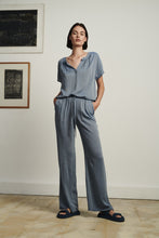 Load image into Gallery viewer, Pants Lola Eco Viscose GBS2222110S van Jane Lushka is een mooie wijde lange broek met striksluiting aan de voorkant en een paspelzak op de achterkant. Broek Lola heeft steekzakken. De broek is uitgevoerd in de kleur blauw. Broek is erg leuk te combineren met de top Remi van Jane Lushka in dezelfde kleur en stof. Hiermee kun je de look creëren van een jumpsuit, maar is natuurlijk ook los van elkaar te dragen. Set is zowel business casual, als casual te dragen, je ziet er stijlvol en vrouwelijk uit.