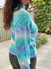 Afbeelding in Gallery-weergave laden, Trui Rain Turquoise/kobalt is een trendy grof gebreide trui met lange pofmouwen, een opstaande kraag en heeft een kabelpatroon op het voorpand. De trui is gemaakt van multicolor garen en is verkrijgbaar in één maat, draagbaar voor maat S/M/L en is verkrijgbaar in verschillende kleuren: Turquoise/kobalt, Roze/geel.