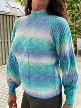 Afbeelding in Gallery-weergave laden, Trui Rain Turquoise/kobalt is een trendy grof gebreide trui met lange pofmouwen, een opstaande kraag en heeft een kabelpatroon op het voorpand. De trui is gemaakt van multicolor garen en is verkrijgbaar in één maat, draagbaar voor maat S/M/L en is verkrijgbaar in verschillende kleuren: Turquoise/kobalt, Roze/geel.