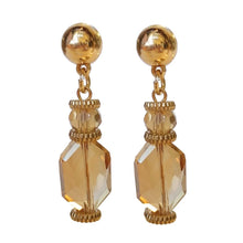 Load image into Gallery viewer, Beige Rose statement oorbellen uit de Veerle Collectie! Deze oorbel is een echte eyecatcher. De oorbellen zijn gemaakt van geslepen kristal en zijn ook nog eens gold dipped. De oorbel is verkrijgbaar in verschillende kleuren: zwart, beige, paars, blauw. De afmeting van de oorbel is 4,7cm x 1cm.