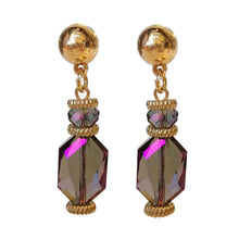 Load image into Gallery viewer, Paarse statement oorbellen uit de Veerle Collectie! Deze oorbel is een echte eyecatcher. De oorbellen zijn gemaakt van geslepen kristal en zijn ook nog eens gold dipped. De oorbel is verkrijgbaar in verschillende kleuren: zwart, beige, paars, blauw. De afmeting van de oorbel is 4,7cm x 1cm.