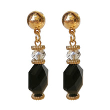 Load image into Gallery viewer, Zwarte statement oorbellen uit de Veerle Collectie! Deze oorbel is een echte eyecatcher. De oorbellen zijn gemaakt van geslepen kristal en zijn ook nog eens gold dipped. De oorbel is verkrijgbaar in verschillende kleuren: zwart, beige, paars, blauw. De afmeting van de oorbel is 4,7cm x 1cm.