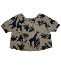 Load image into Gallery viewer, Linnen Top van Moment by Moment, achterkant top. De top valt wijd, heeft een ronde hals en een touwtje om eventueel te strikken. Deze zandkleurige top heeft een korte mouw en een super mooie jungle print. Is als pak te dragen samen met dezelfde print broek, maar kan ook gecombineerd worden met een zwarte travelbroek van Jane Lushka.