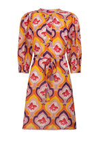 Load image into Gallery viewer, Jurk van Place du Soleil, Retro Fish is een prachtig kleurrijk middellang iets uitlopend model jurk met knoopjes en steekzakken, 3/4 mouwen met elastiek en een ronde kraag, die afgewerkt is met paarse band. De jurk heeft een onderjurk, is een mooi kleurenpalet en heeft een retro print. De jurk heeft een losse ceintuur in dezelfde print met gekleurde flosjes.