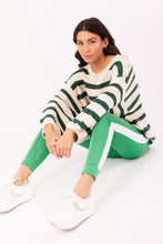 Afbeelding in Gallery-weergave laden, Gestreepte trui, grof gebreide gestreepte trui, wijder model, met als leuk detail goudkleurige knopen op weerszijde schouders en de trui heeft een ronde hals. Deze trui is verkrijgbaar in verschillende kleuren: groen/ecru, camel/ecru, zwart/ecru.