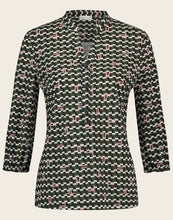 Load image into Gallery viewer, Topblouse Cruz van Jane Lushka, Blouse Cruz UJK72226090 heeft een V-hals, drie knoopjes, 3/4 mouw met elastieken boord. De blouse is in retrostijl en de basis kleur van deze topblouse is Army green, heeft een leuk patroon met blokjes in de kleuren, zwart en wit, met het logo van Jane Lushka in roze. De blouse is in de bekende travel kwaliteit. Blouse Cruz is goed te combineren met de Pants Annabel in Armygreen. Een pracht van een casual set, vrouwelijk, speels en stijlvol.