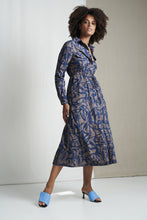 Afbeelding in Gallery-weergave laden, Dress Linna UK92224040 van Jane Lushka is een prachtige jurk van de bekende travel kwaliteit. Jurk Linna is een lange doorknoopjurk met kraag in print kleurstelling, bruin, donkerblauw en fel blauw als klein detail. Jurk heeft lange mouwen en een rijgkoord in de taille.