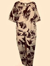Load image into Gallery viewer, Linnen Top van Moment by Moment, achterkant top. De top valt wijd, heeft een ronde hals en een touwtje om eventueel te strikken. Deze zandkleurige top heeft een korte mouw en een super mooie jungle print. Is als pak te dragen samen met dezelfde print broek, maar kan ook gecombineerd worden met een zwarte travelbroek van Jane Lushka.