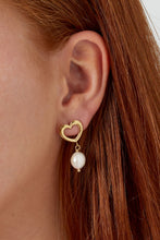 Load image into Gallery viewer, Goudkleurige Oorbellen van stainless steel, type oorstekers. Open hartvormige oorbellen met parel als bedel. Een mooie klassieke oorbel. Afmeting oorbel is 1.40cm x 3cm.
