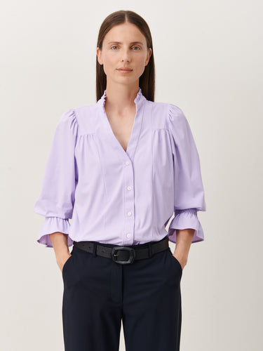 Paarse Blouse, Olivia Blouse Lila U724229 van de Jane Lushka Collectie is een vrouwelijke blouse met knoopjes, heeft een V-hals met ruffles en plooitjes op het voor en achterpand, als mooi detail. Met een gepofte 3/4 mouw en elastiek smokwerk. 