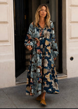 Load image into Gallery viewer, Multicolor Jurk Kerman Milotic van Banditas van Marseille. De lange jurk is een licht klokkend model met bloemmotief, lange ballon mouwen en elastieken manchetten. Deze jurk heeft werkelijk een prachtige print in kleurcombinatie bruine en blauwe tinten. Jurk heeft knoopjes, die zowel gesloten als open gedragen kunnen worden, voor een luchtig effect.
