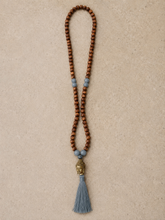 Load image into Gallery viewer, Ketting van Hot Lava is een mooie ketting met bruine kraaltjes en een aantal contrasterende kraaltjes, een buddha gezicht en een gekleurde franje in verschillende kleuren.
