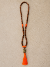 Load image into Gallery viewer, Ketting van Hot Lava is een mooie ketting met bruine kraaltjes en een aantal contrasterende kraaltjes, een buddha gezicht en een gekleurde franje in verschillende kleuren.
