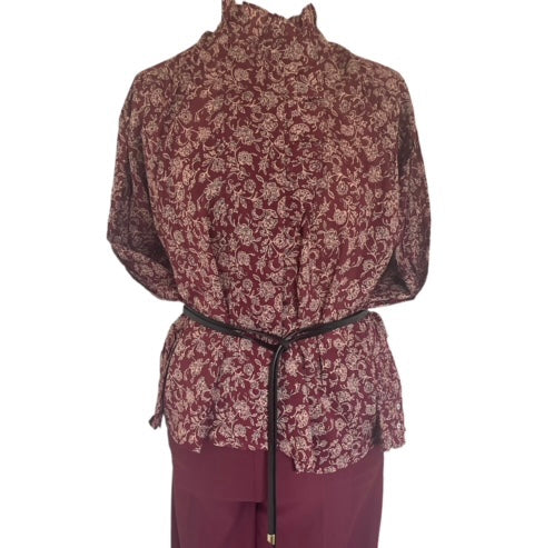 Wijnrode Blouse van Moment Amsterdam met referentie 57.100-23, is een prachtige romantische blouse met bloemenprint. Deze blouse heeft een opstaande kraag met ruffles aan de hals en mouwen. Deze blouse is mooi te combineren met de Corel Broek Lily Wide Uni Sport Beetroot.