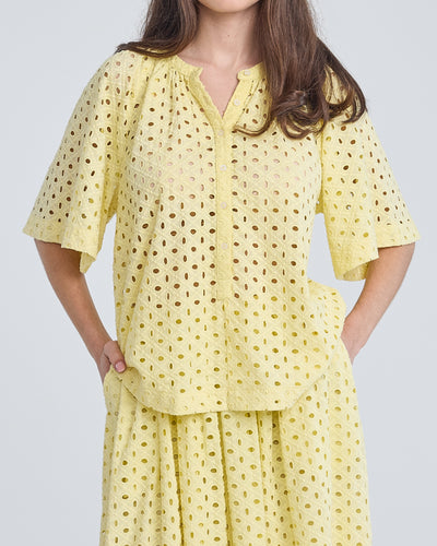 Gele Blouse Top Blanca van de Moment Amsterdam Collectie is een top met een ronde hals en een korte vlindermouw in een prachtige zomerse kleur. Deze katoenen blouse top heeft knoopjes tot halverwege de blouse en een gaatjes patroon met geborduurde bloemen.