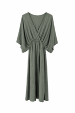 Load image into Gallery viewer, Groene Jurk Dominique met subtiele glans en split. Een zomerse Jurk met een flatterende V-hals en een elegante overslag, elastische taille, gecombineerd met wijde mouwen voor een luchtige en vrouwelijke uitstraling.
