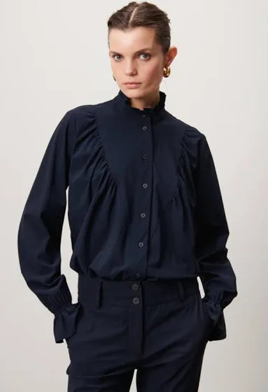 Blauwe Blouse Roberta U723120 van Jane Lushka is een verfijnde elegante blouse. Blouse heeft ruffles aan de voorkant, een hoge kraag, lange mouwen, donkere knoopjes. Deze stijlvolle blouse is ook ontzettend mooi om te dragen onder een pak. De blouse is van de bekende travel kwaliteit en is verkrijgbaar in fuchsia, blauw.