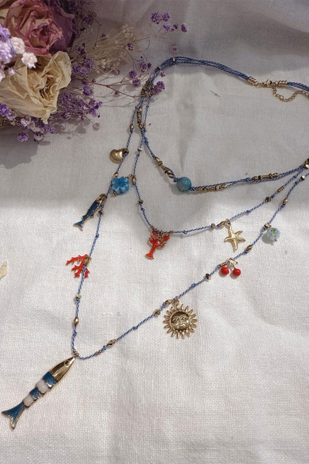 Lange bedel ketting, 3 lagen met goudkleurige en gekleurde bedels en een hanger van een goudkleurige turquoise vis. Een prachtige lange ketting van 60cm.