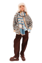 Afbeelding in Gallery-weergave laden, Teddy jas met een moderne twist voelt zacht en luxe aan, terwijl de horizontale strepen in blauw, bruin en ecru de jas een eigentijdse uitstraling geven.
