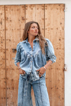 Afbeelding in Gallery-weergave laden, Denim Blouse Pancha Blue van ibzmode heeft een kraagje, sluit met de knopen, heeft gerafelde afwerkingen, elastiek bij de polsen en is geplooid bij de borsten. De gerafelde afwerkingen en elastiek bij de polsen geven een speelse twist aan het klassieke ontwerp. Verkrijgbaar in verschillende kleuren: Off White, Blue.
