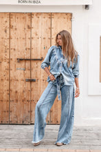 Afbeelding in Gallery-weergave laden, Denim Blouse Pancha Blue van ibzmode heeft een kraagje, sluit met de knopen, heeft gerafelde afwerkingen, elastiek bij de polsen en is geplooid bij de borsten. De gerafelde afwerkingen en elastiek bij de polsen geven een speelse twist aan het klassieke ontwerp. Verkrijgbaar in verschillende kleuren: Off White, Blue.
