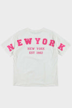 Afbeelding in Gallery-weergave laden, Wit T-shirt New York is een basis shirt van 100% katoen met ronde boord en korte mouwen. Op de achterkant heeft dit t-shirt een applicatie met letters NEW YORK in roze. T-shirt New York is verkrijgbaar in verschillende kleuren: Wit/roze, Rood/wit, Geel/wit.
