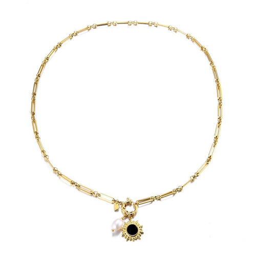 Ketting van Sweet 7 heeft een platte schakel met een oogje waaraan 2 bedels hangen, een witte parel en een zon met zwarte steen.